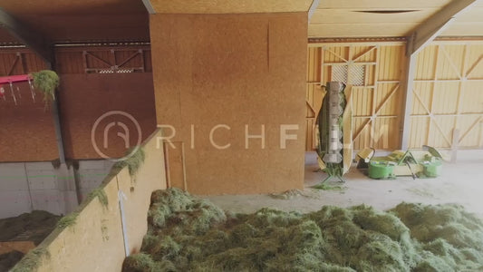 Aerial view of a hay store with a gripper arm picking up hay