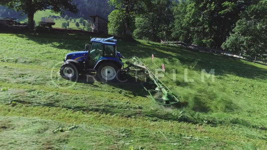 Aerial view of a tractor turning grass in the field