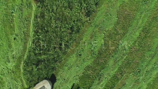 Aerial view of a tractor in the field mowing bird's eye view