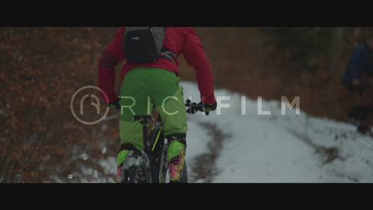 Shot of a mountain biker riding through a forest with snow thrown out of the rear tyres