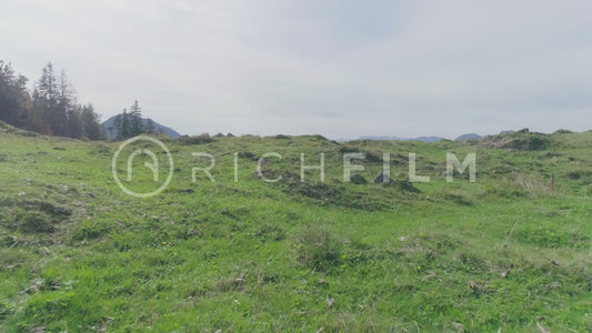 Aerial shots of mountain bikers riding over a hill with mountains in the background in summer