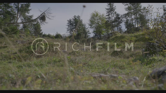 shot of two mountain bikers riding over a hilly field from the ground perspective