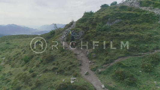 Aerial view of a mountain biker carrying his bike on his back up the mountain