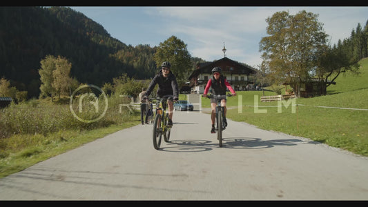 Shot of two mountain bikers riding on the road next to a lake