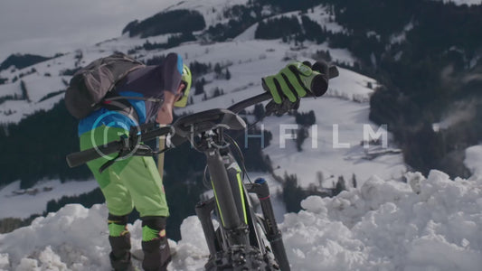 Slow motion shot of a mountain biker scooping snow behind his bike