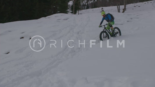 Slow-motion shot of a mountain biker in deep snow