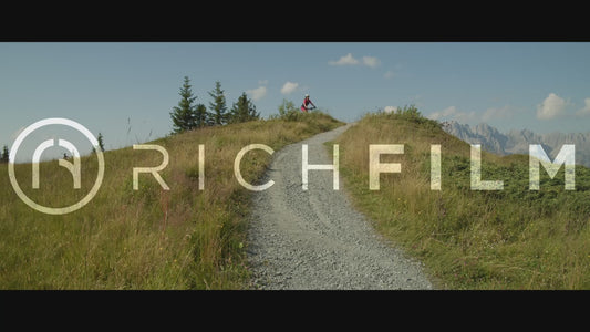 Slow-motion shot of a mountain biker riding over a hill and being pelted with stones from his rear tyre