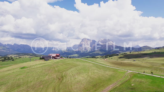 Aerial view in the Dolomites with inn, hilly landscape, forest and cloudy sky