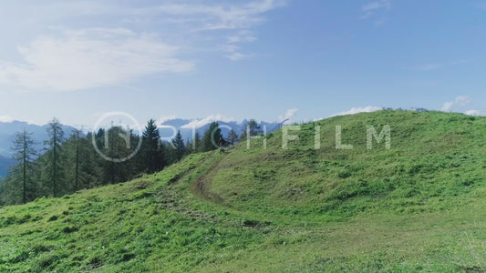 Aerial view of a mountain biker riding across a small field in summer