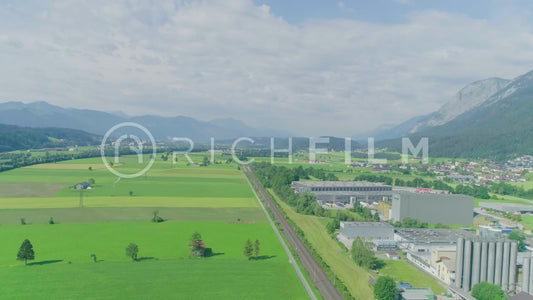 Aerial view of an industrial area and fields with cloudy sky and mountains