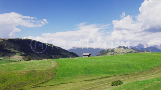 Aerial view of a hilly landscape with a cloudy sky and a wooden hut