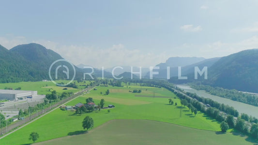 Aerial view of a field with mountains, cloudy sky and an industrial area