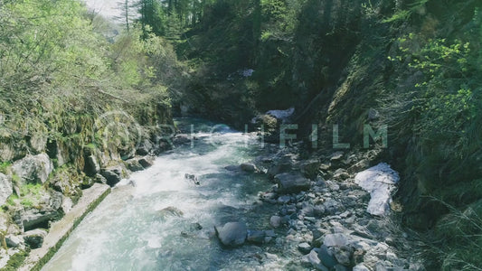 Aerial view of a blue stream with trees and stones