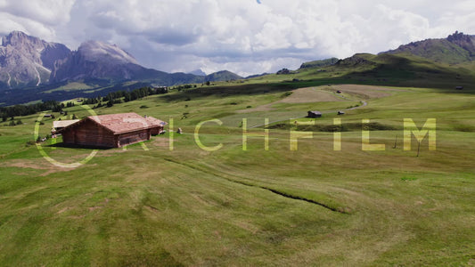 drone shots of a mountain landscape with wooden huts and cloudy sky