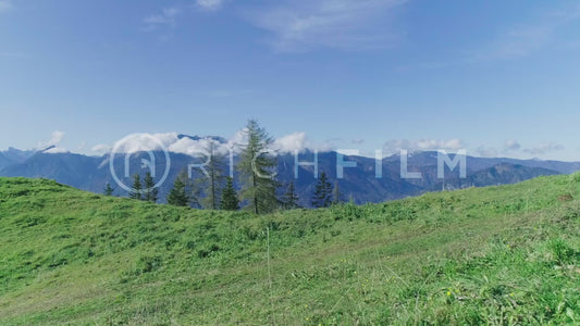 Shot of a mountain biker riding along a dirt track in summer with the mountains and cloudy sky in the background