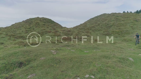 Aerial view of a mountain biker riding over a hill with a view of the landscape