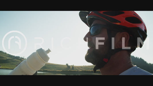 Slow motion shot of a cyclist drinking from his water bottle and the sun shining through