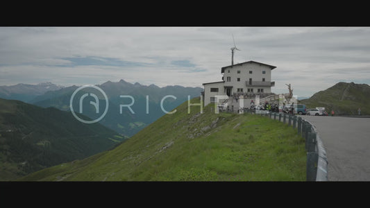 Shot of a house with wind turbine and view of mountains and cloudy sky