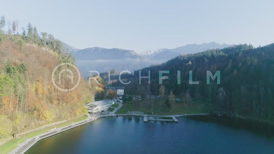 Shot of a lake with rays of light in the blue water and clear sky with mountains and orange forest - V3