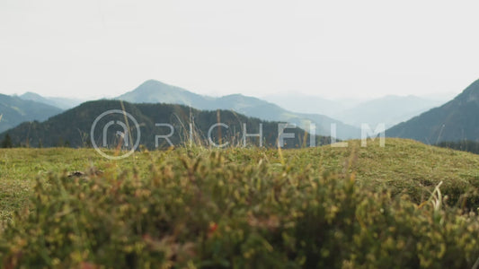 shot of a mountain biker riding over a hill with the mountains in the background