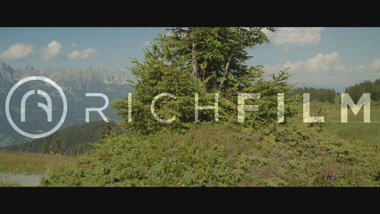 Slow-motion shot of a cyclist with camera panning while turning on a forest path in summer