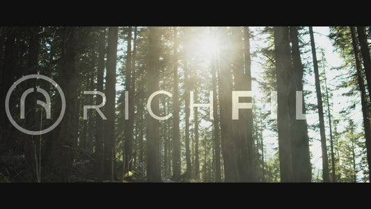 Shot of mountain bikers riding through a forest in the Alps while the sun shines through the trees