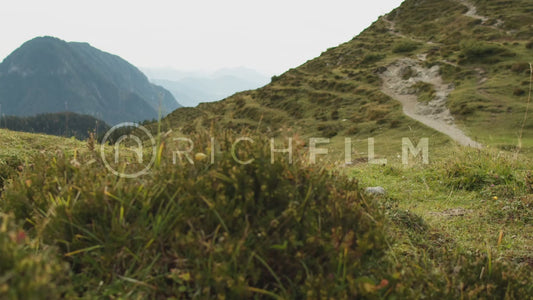 shot of a mountain biker riding over a hill with the mountains in the background - V2