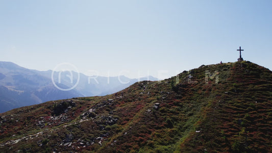 Drone shot of a mountain peak with mountains in the background and blue sky