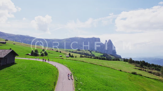 Aerial view of the Dolomites with hilly landscape and a hut with path and hiker