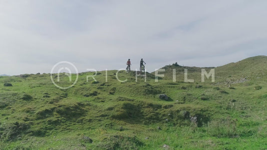 Aerial shots of mountain bikers standing on a hill with the mountainous landscape in the background