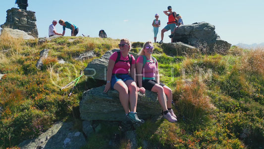 Aerial view of people sitting at a summit cross with mountains in the background