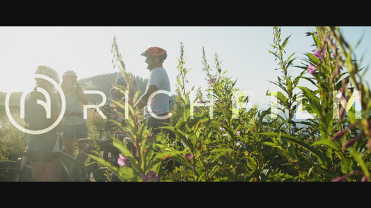 Slow motion shot of cyclists standing together in the sun in the field with their bikes