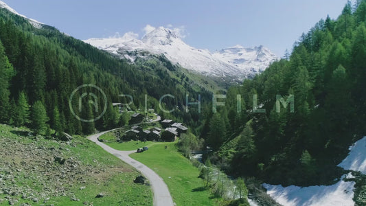 Aerial view of a village in the middle of the Alps with forests and mountains