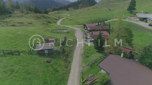 Aerial view of bikers riding through houses on a mountain range with the alps in the background