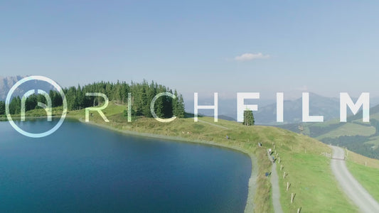 aerial view of cyclists cycling around a lake in summer with a clear sky and a hilly landscape