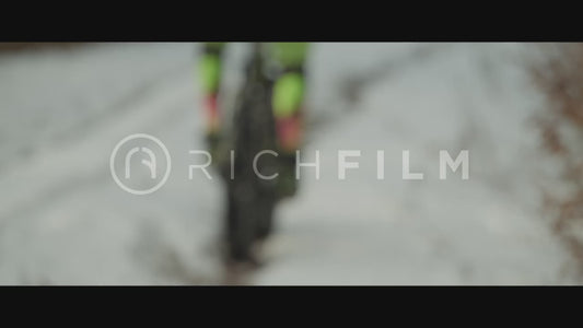 Slow motion shot of a mountain biker riding through a snow-covered forest