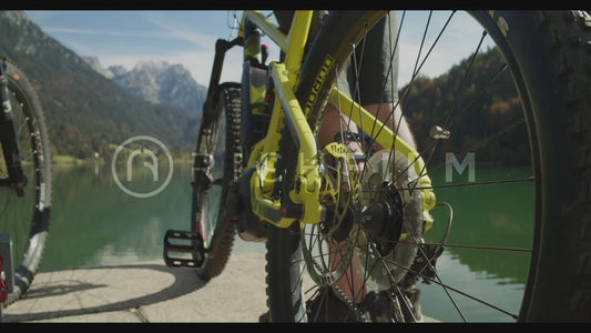 Aufnahme von zwei Mountainbikern, die sich unterhalten und auf einen See und Berge blicken