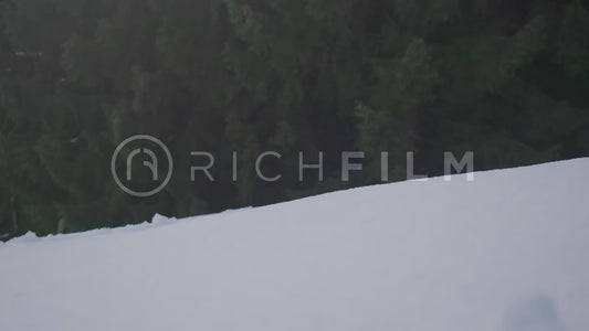 Slow motion shot of a mountain biker riding down a snow-covered hill, front view in winte