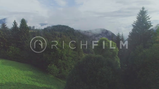 Aerial view in the mountains of Austria with forest and cloudy sky