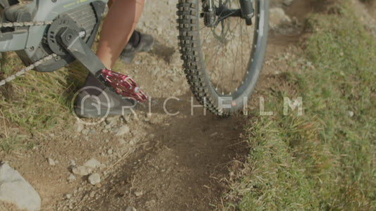 Biker pushes bike downhill on a sunny day