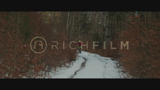 Shot of a mountain biker on a forest path with bushes Winter rides - V2